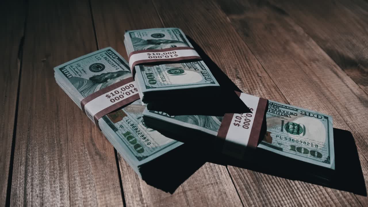 Three Stacks of 10000 American Dollars Banknotes in Bundles Lie on Wooden Table