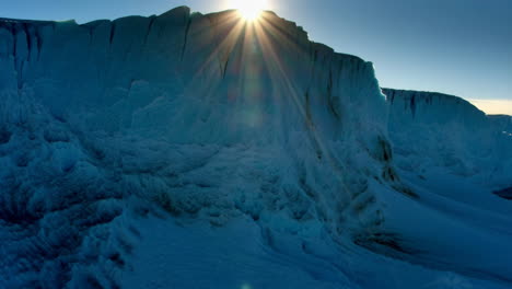 sunburst over a massive blue glacier or iceberg cliff