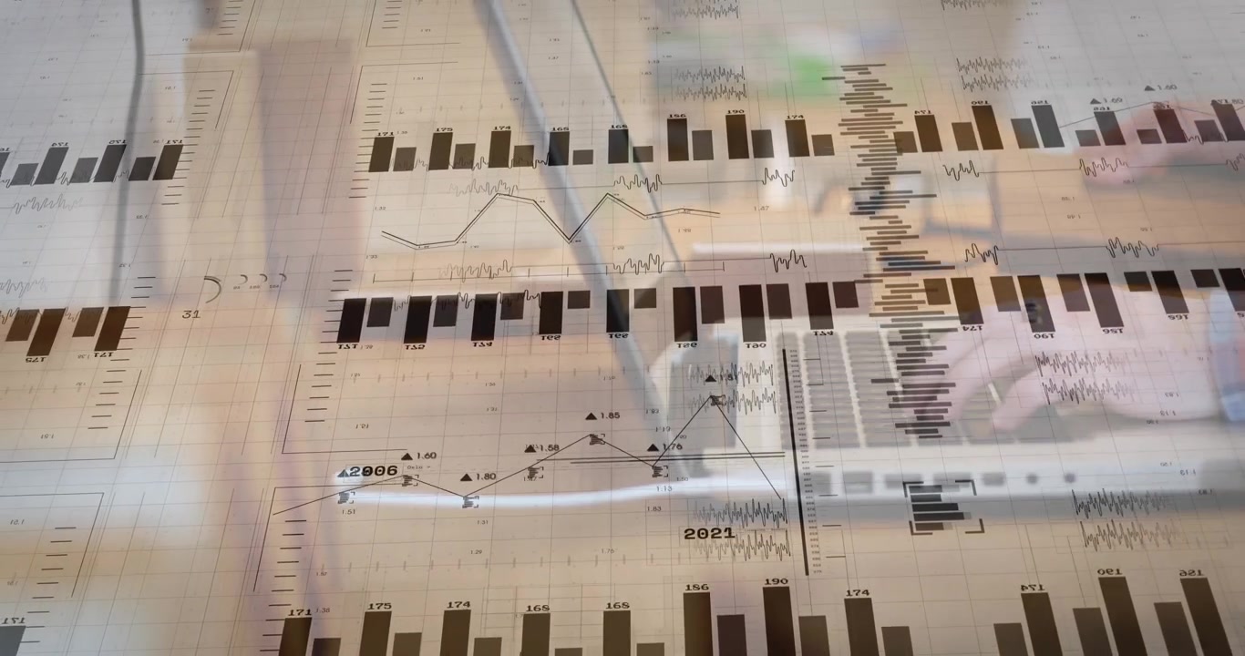 Financial charts and graphs floating above laptop keyboard on office desk, typing hands adding data