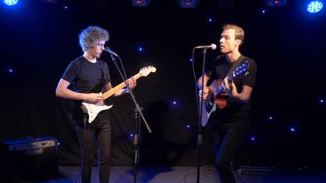 concert rock band performing on stage with two electric guitars singers. music video punk, heavy metal or rock group. slow motion instrument playing band of two men