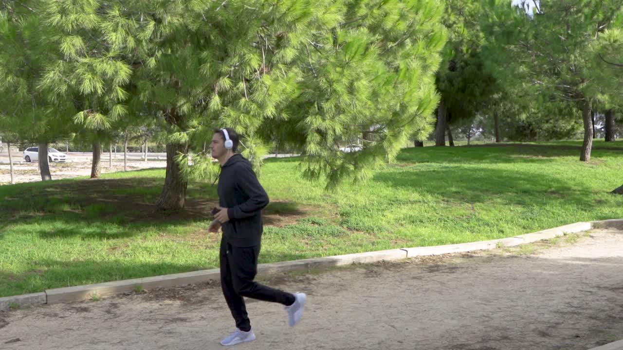 Un uomo guarda il cellulare al parco e inizia a fare jogging