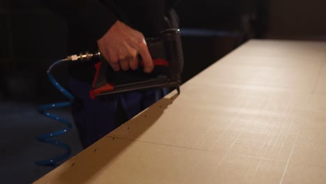 persona que usa una pistola de clavos en un panel de madera