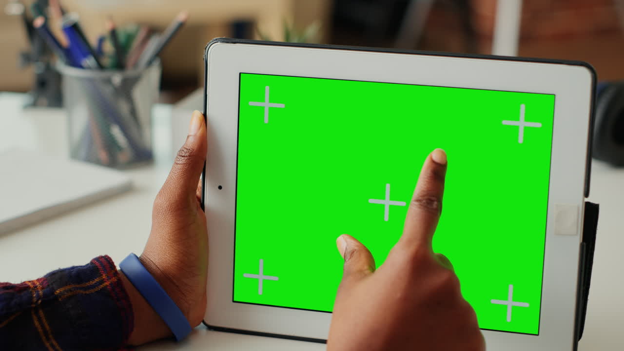 Young worker looking at horizontal greenscreen display on tablet