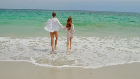 rear view of caucasian couple running on the beach 4k