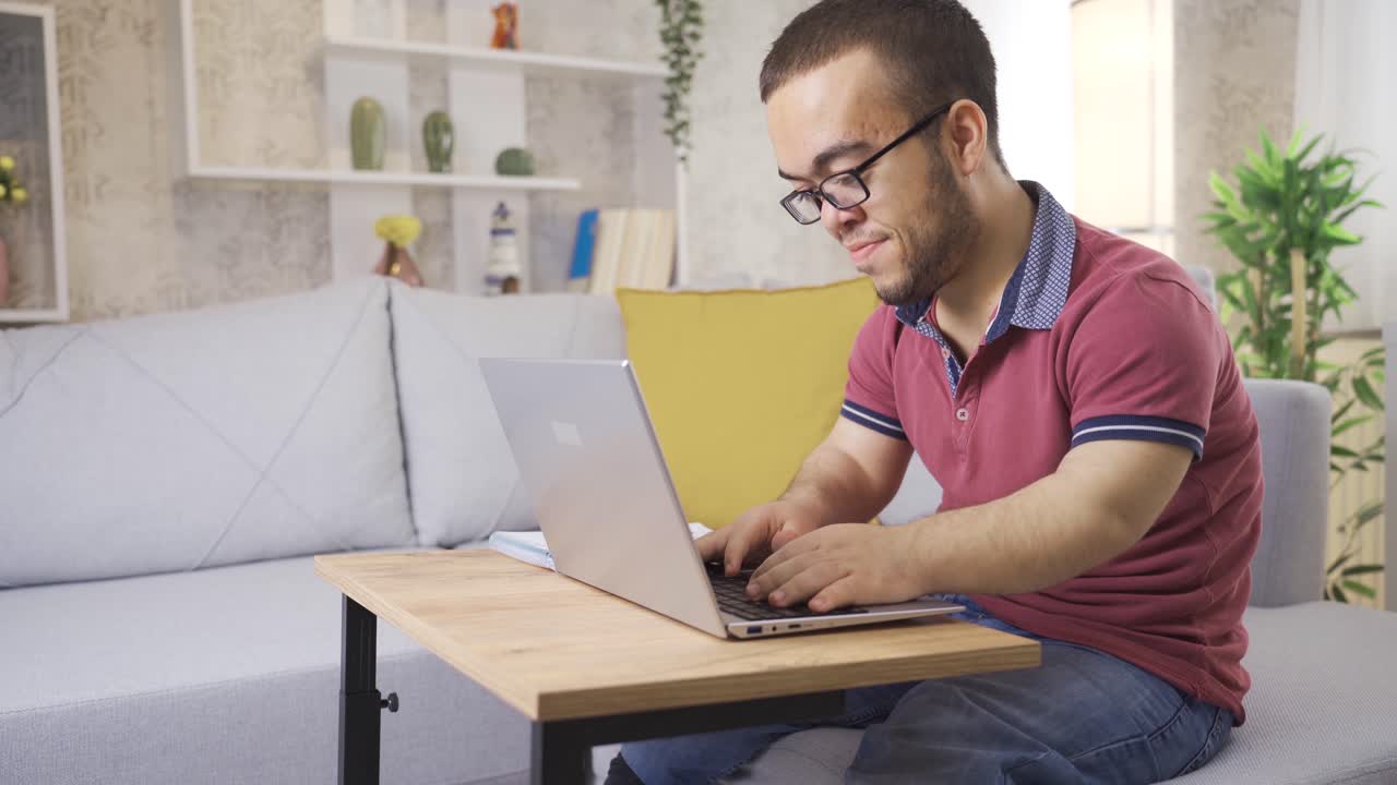 un joven enano feliz y alegre usando una computadora portátil en casa.