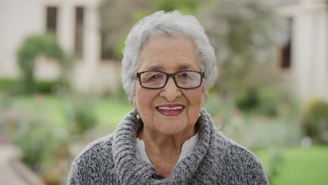 Retrato-De-Una-Anciana-Jubilada-Sonriendo-Feliz-Mirando-La-Cámara-Con-Gafas-Disfrutando-Del-Soleado-Jardín