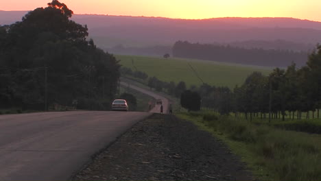 Los-Vehículos-Viajan-Por-Una-Carretera-Rural-Cerca-Del-Atardecer.