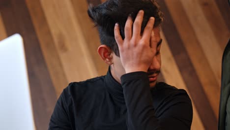 estudiante preocupado y estresado trabajando en una computadora portátil en una cafetería