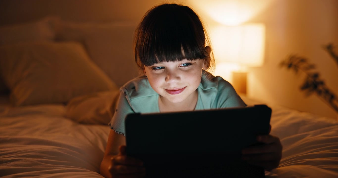 Young Girl Using Tablet in Bed at Night