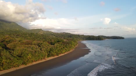 Drone,-Moving-In-across-Sandy-beaches,-with-tropical-forest-and-mountains