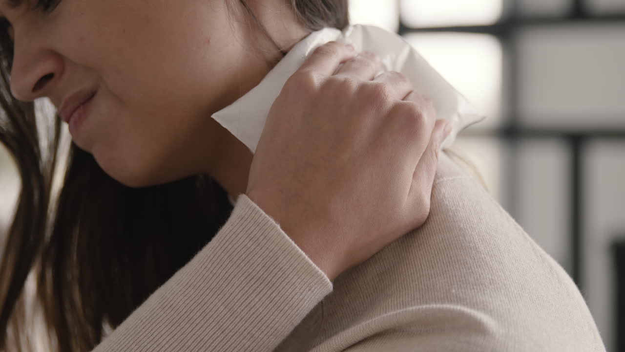 집에서 얼음 팩으로 목 통증을 완화하려는 고통받는 여성을 닫습니다