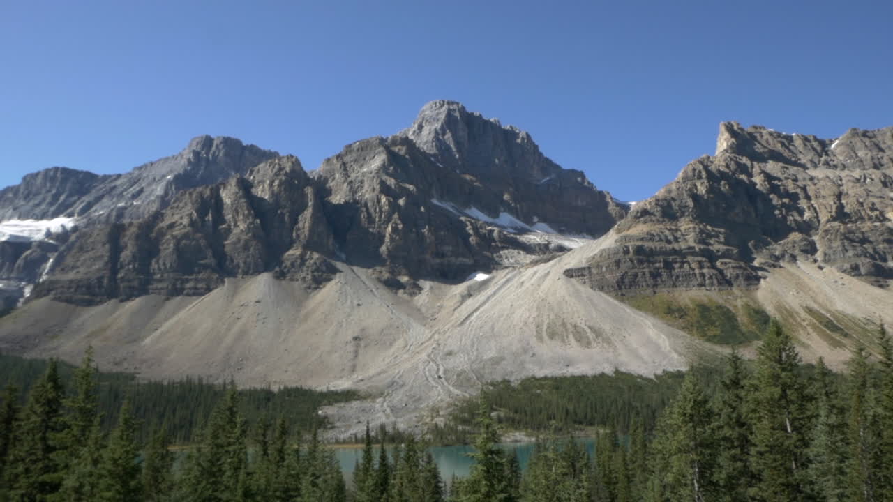 paisaje montañoso canadiense, con nieve, bosque de pinos y lago glaciar
