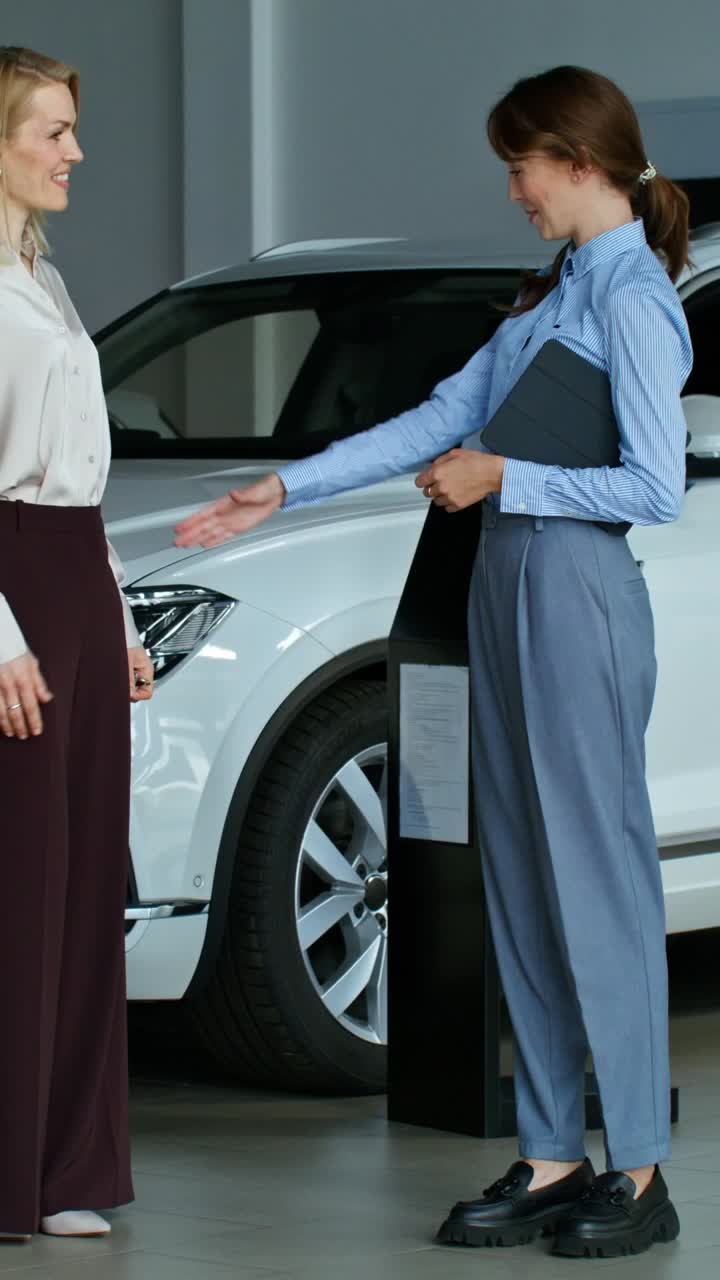 dos mujeres discutiendo una compra de coche en una sala de exposiciones