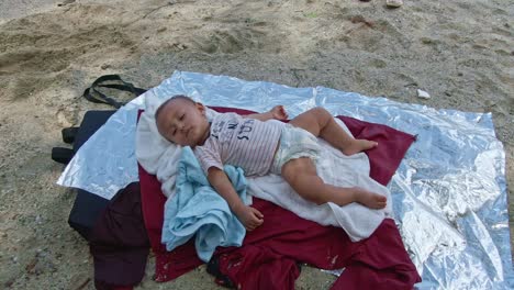 baby calmly sleeping in the blanket by the white beach