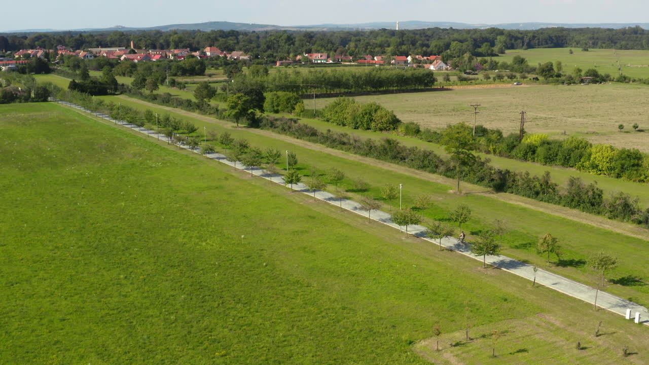 시골의 나무 골목길에서 자전거를 타는 두 사람, 긴 드론 샷