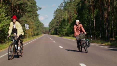 couple cycling on a road through a forest