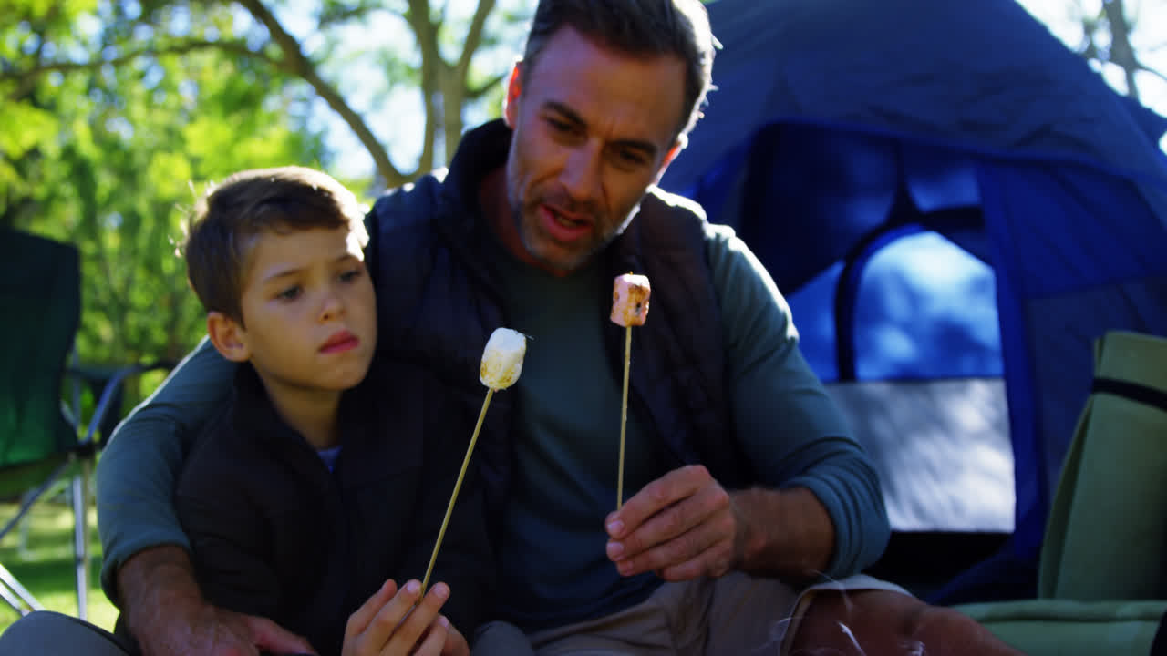padre e hijo asando malvaviscos fuera de la tienda