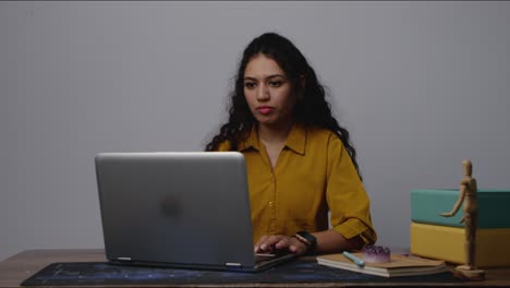 a smiling south asian woman working on her laptop, celebrating a breakthrough after solving a problem during a productive office session