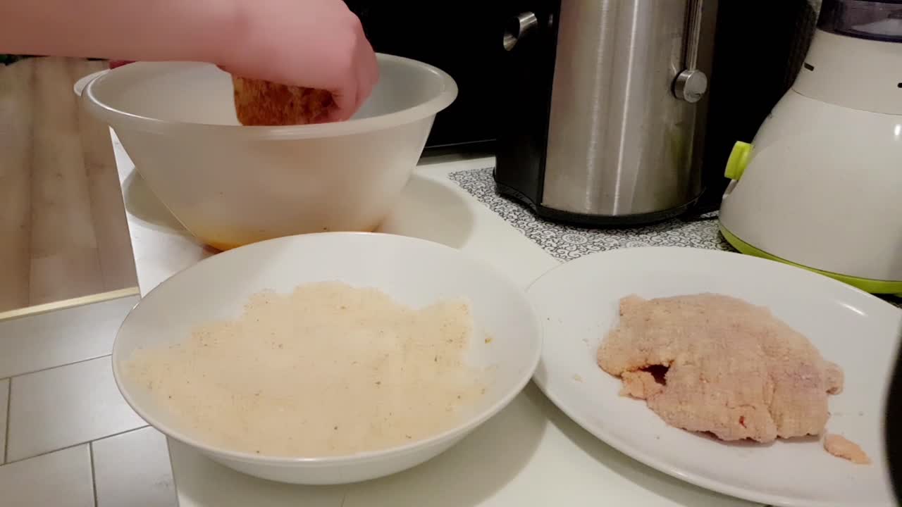 전통적인 헝가리 빵 가루 입힌 돼지 고기 조각을 만들기 위해 돼지 고기를 빵가루 입힌 백인 여자