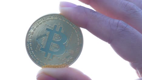 Closeup-of-a-Hand-holding-a-Physical-Bitcoin-with-Thumb-and-Index-Finger