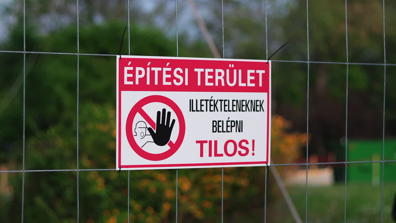 Hungarian No Trespassing sign hanging on fence. Blurred background