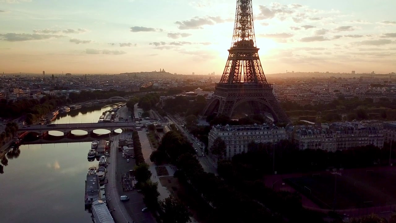 Ripresa verticale con drone in ascesa: di fronte alla Torre Eiffel con il sole alle spalle, all'alba, sopra il fiume Senna