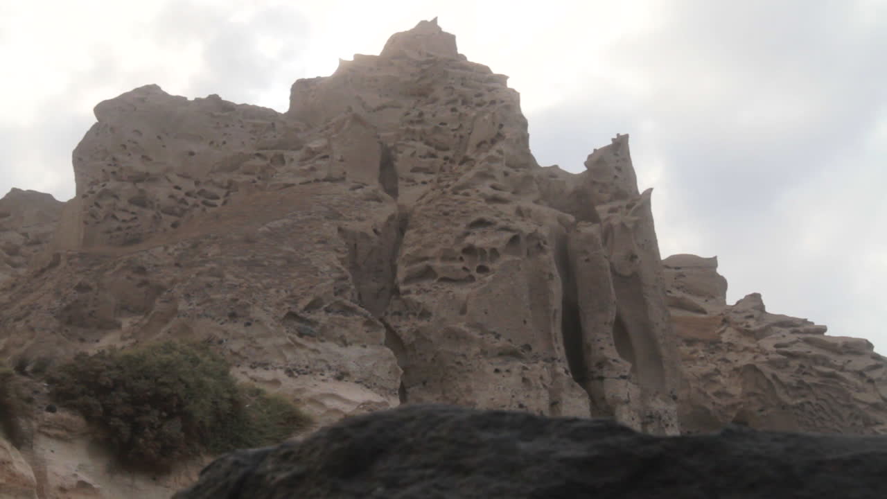 toma de seguimiento de formaciones de acantilados volcánicos blancos en una playa negra en santorini