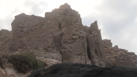 tracking shot of white volcanic cliff formations on a black beach at santorini