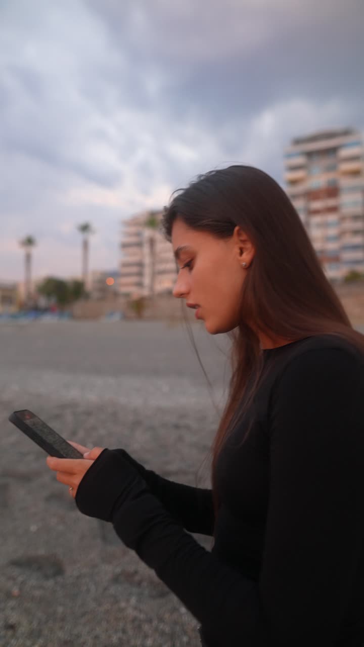 joven mirando su teléfono inteligente en la playa