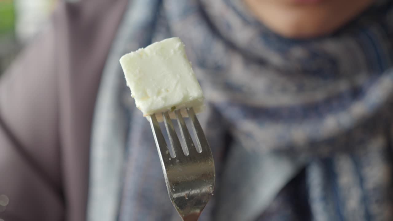 Detail kousku sýra feta na vidličce držené osobou