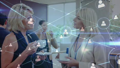 animation of network of profile icons over two caucasian businesswomen discussing at office