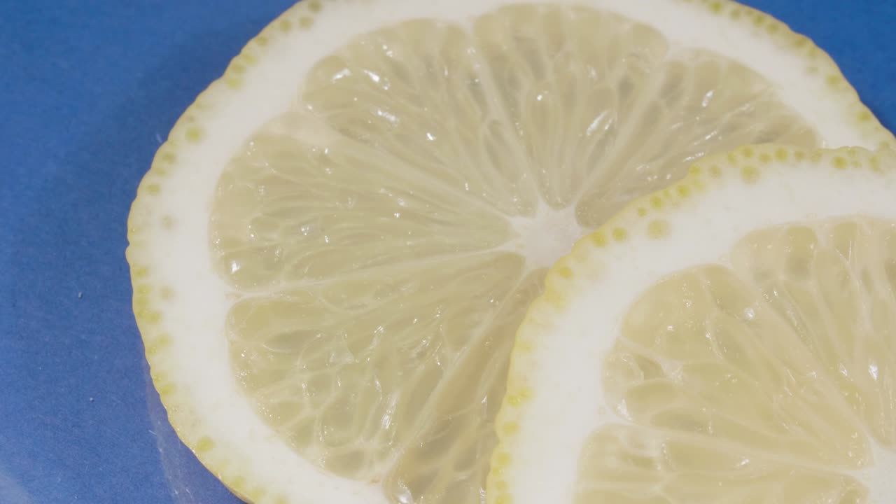 Lemon slices close-up. Blue background. 4K video . Citrus fruit.