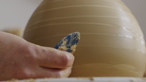 Handheld-close-up-shot-of-working-with-a-scraper-on-a-clay-vase