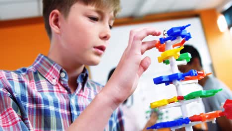 Schoolboy-experimenting-molecule-model-in-laboratory-at-school