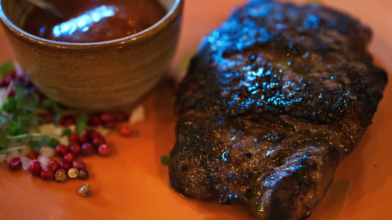 Close up of a piece of grilled beef on an orange plate at a restaurant