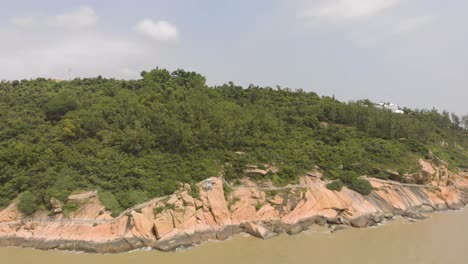 Aerial-shot-following-the-coastline-and-revealing-traditional-Chinese-pavilion-in-distance