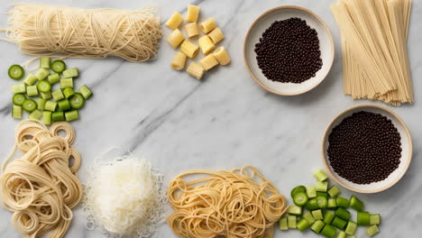 assortment of raw noodles and cooking ingredients on a marble background