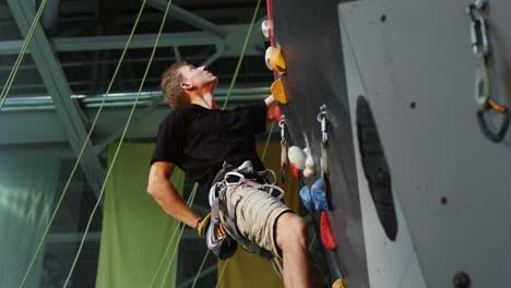 hombre escalando roca en una pared de escalada interior