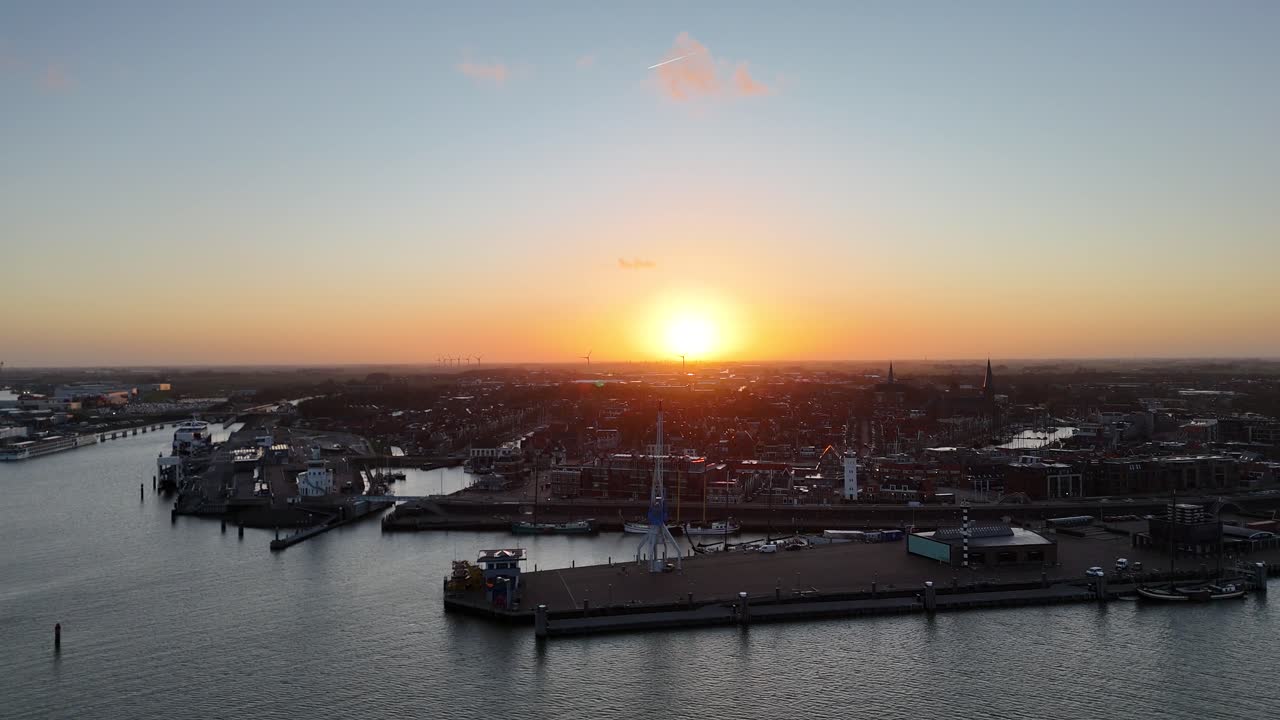 Drönarflygning i gryningen förbi hamnkranen med den uppgående solen över Harlingen.