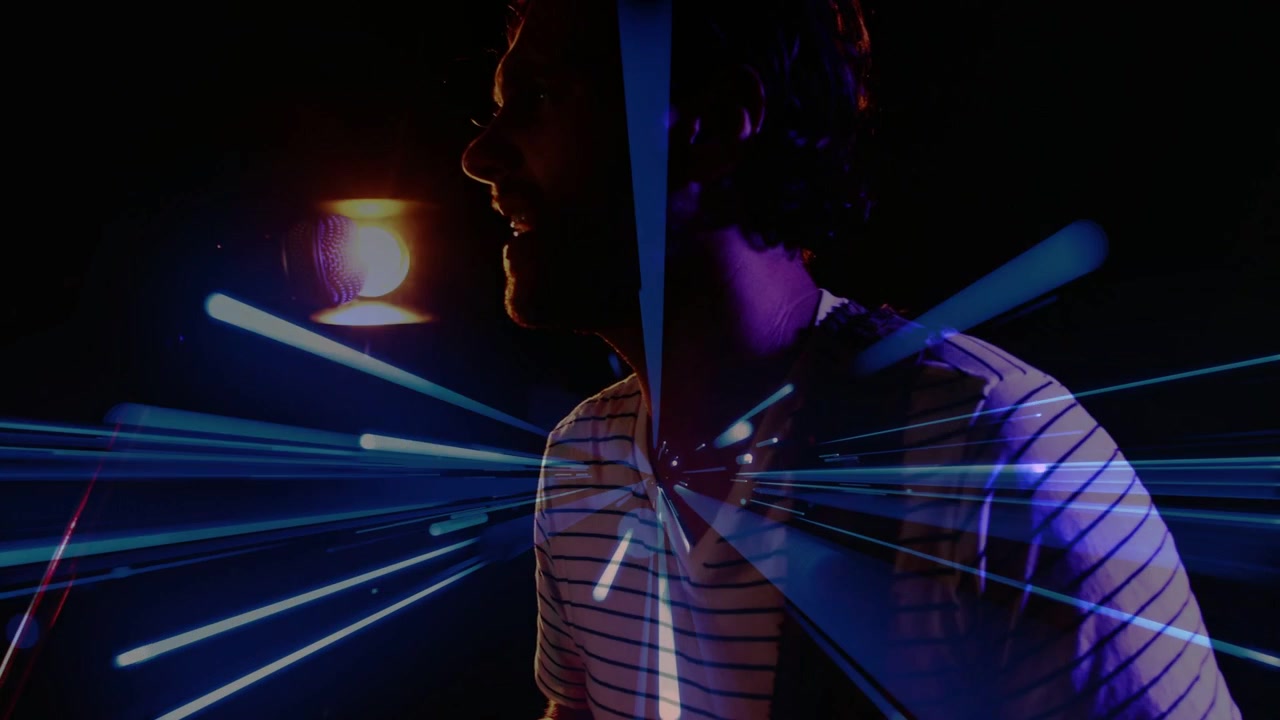 Camera panning up man strumming guitar leaning to mic singing blue-teal radial streaks overlaying