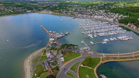 perros-guirec harbor with sailboats, coastal town, causeway, and green countryside, brittany, france. aerial drone sideways