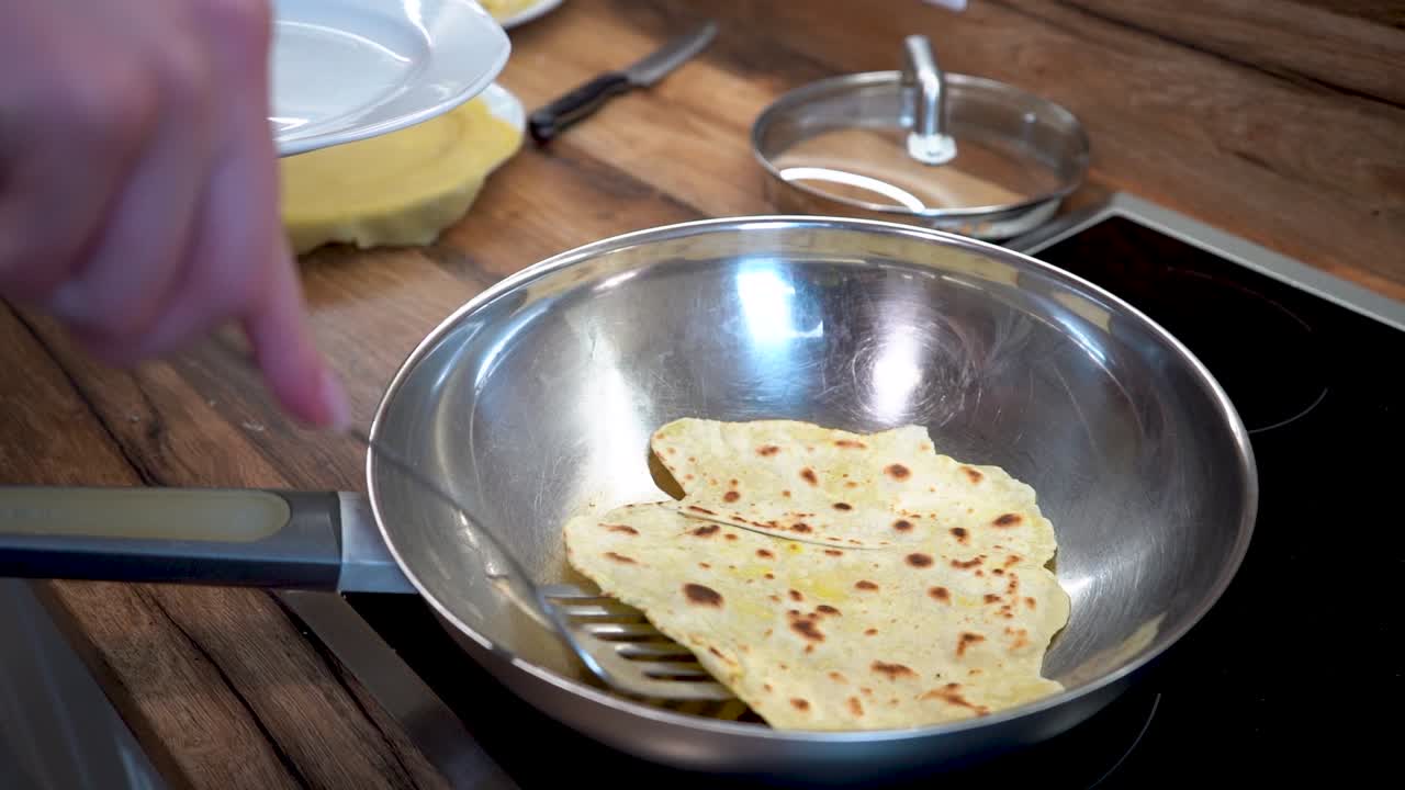 Mano di donna che mette un pezzo di impasto per tortilla da una padella a un piatto