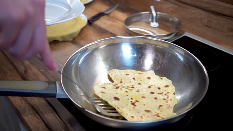 Die-Hand-Einer-Frau-Legt-Eine-Scheibe-Tortilla-Teig-Aus-Einer-Bratpfanne-Auf-Einen-Teller