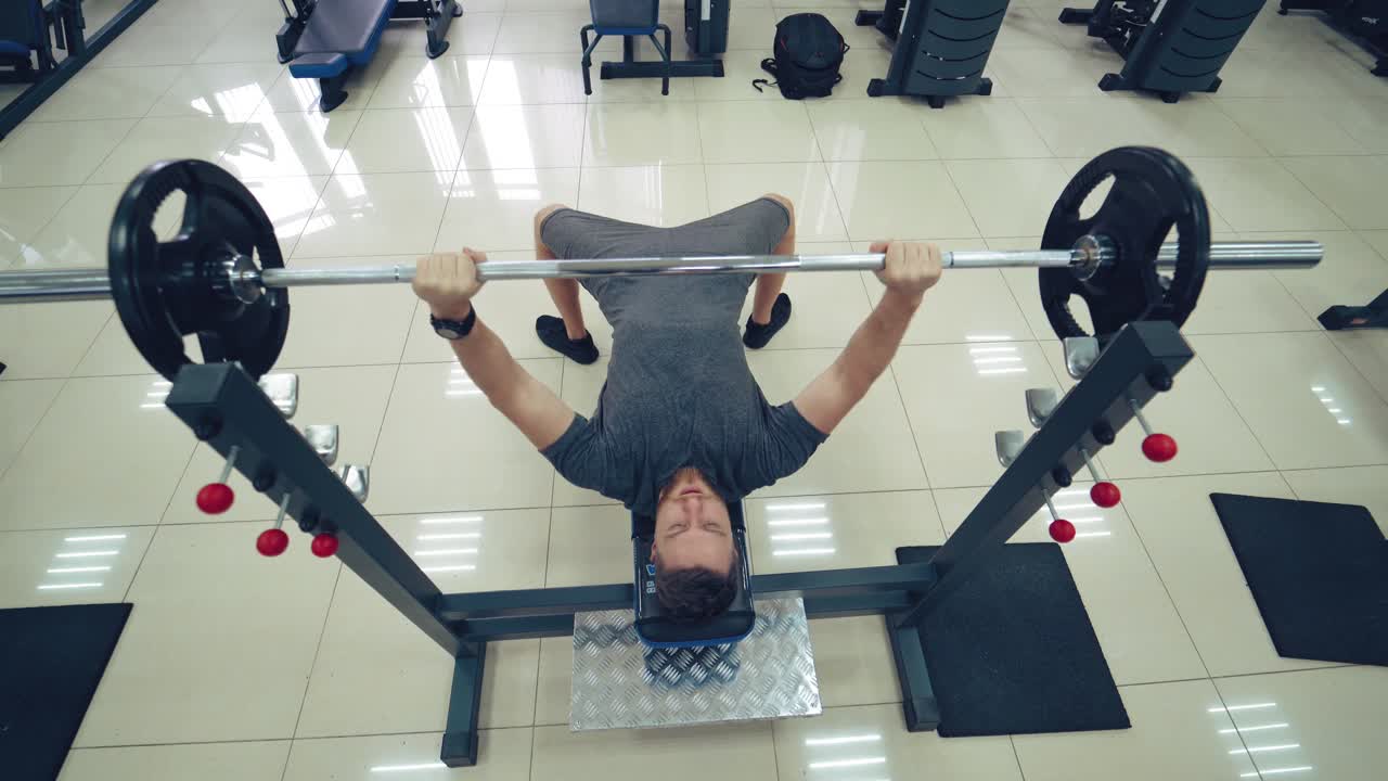 Handsome Man Is Working Out Chest With Barbell In A Modern Gym