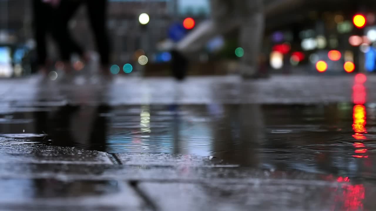 Close-up of raindrops falling in puddles on the road, slow motion ...