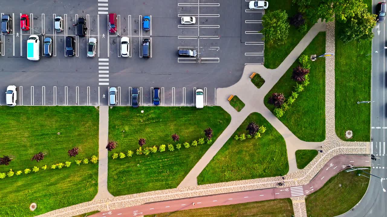Top-down aerial view of parking lot and green park with sidewalks and walking paths