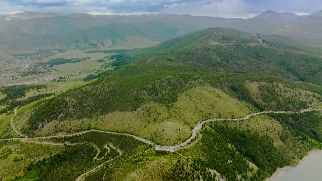 Sinuate road going round the hill covered with pine trees. Scenic picture of beautiful mountains of Colorado, USA. Aerial view.