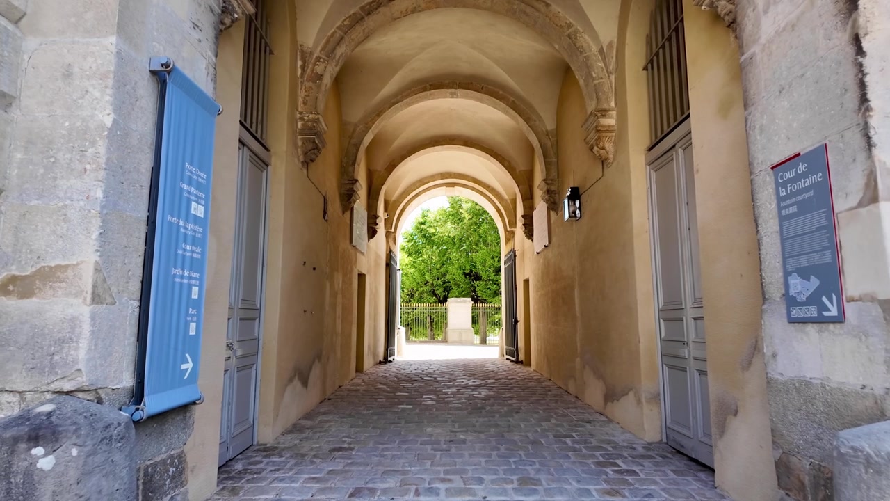 Corridoio in pietra e arco a volta che si apre verso i giardini del Palazzo di Fontainebleau in Francia in una giornata di sole