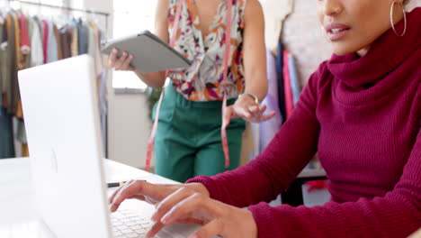 Felices-Y-Diversas-Diseñadoras-De-Moda-Usando-Laptop-Y-Tableta-Discutiendo-En-El-Estudio,-Cámara-Lenta