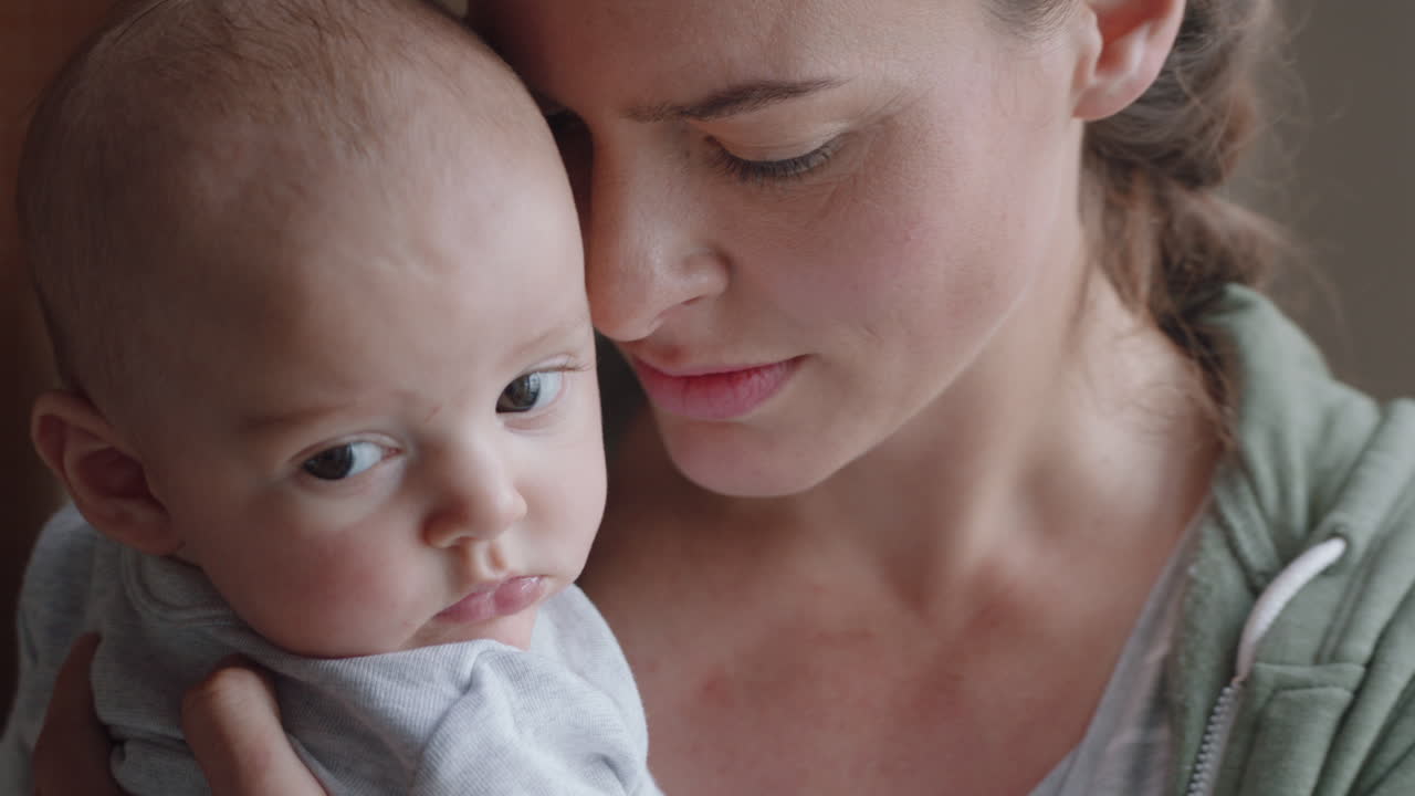 집 에서 아기 를 안고 있는 젊은 어머니 는 신생아 를 진정 시키며 어머니 는 아기 를 부드럽게 진정 시키며 양육 하는 어머니 를 즐긴다